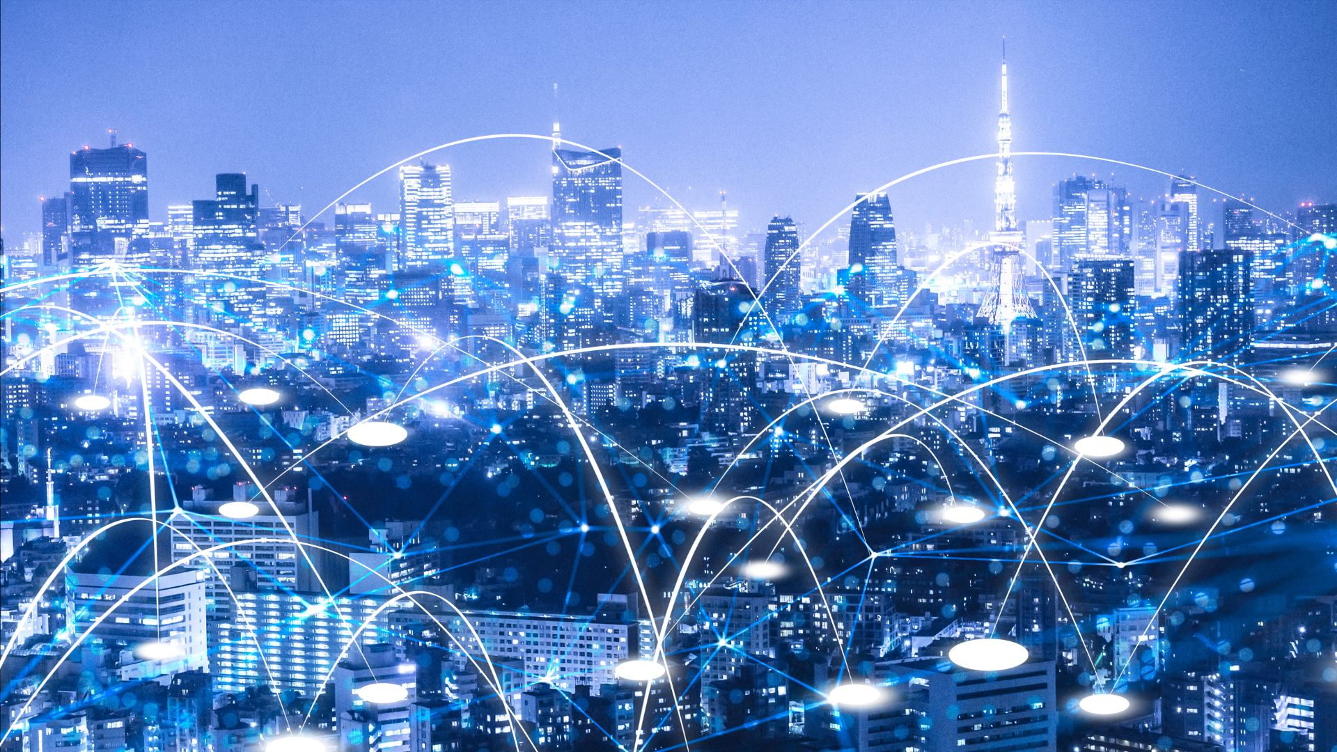 Cidade iluminada à noite com linhas digitais representando conexões de rede e transmissão de dados.