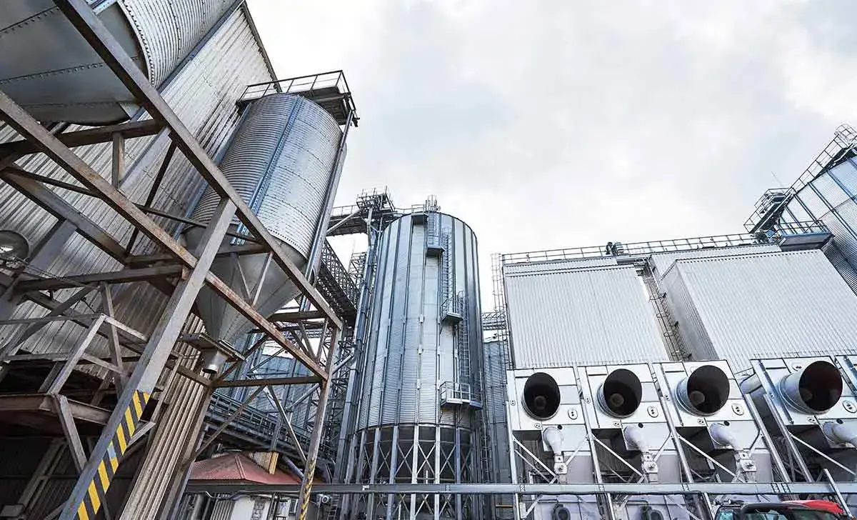 Estrutura industrial com silos metálicos e equipamentos de processamento.