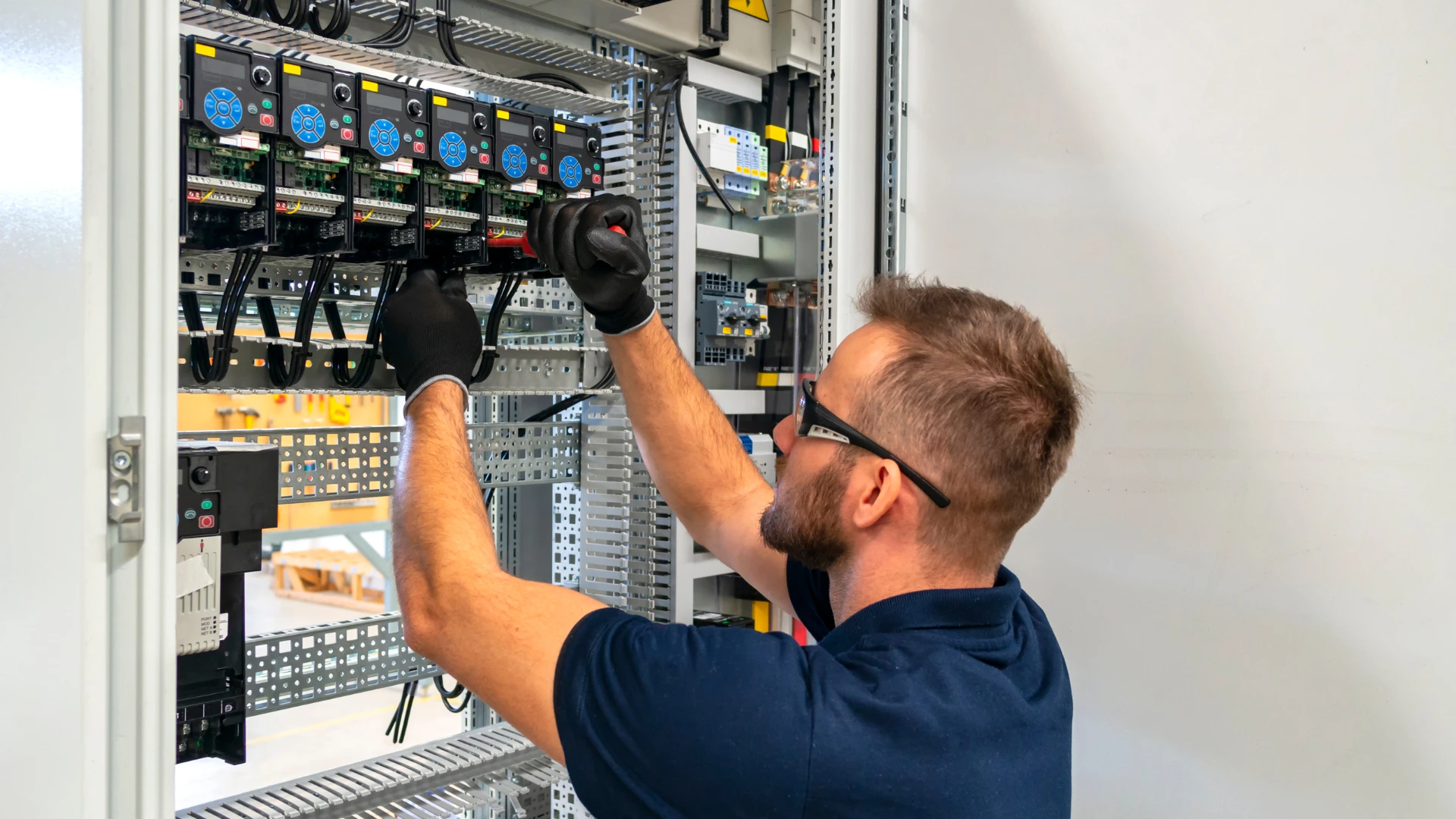Eletricista realizando manutenção em painel elétrico industrial com inversores de frequência