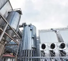 Profissionais com capacete analisando tablet em ambiente industrial.